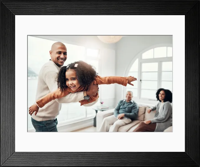 Framed Print : Family, flying and a father playing with his daughter in the living room of their home together during a visit