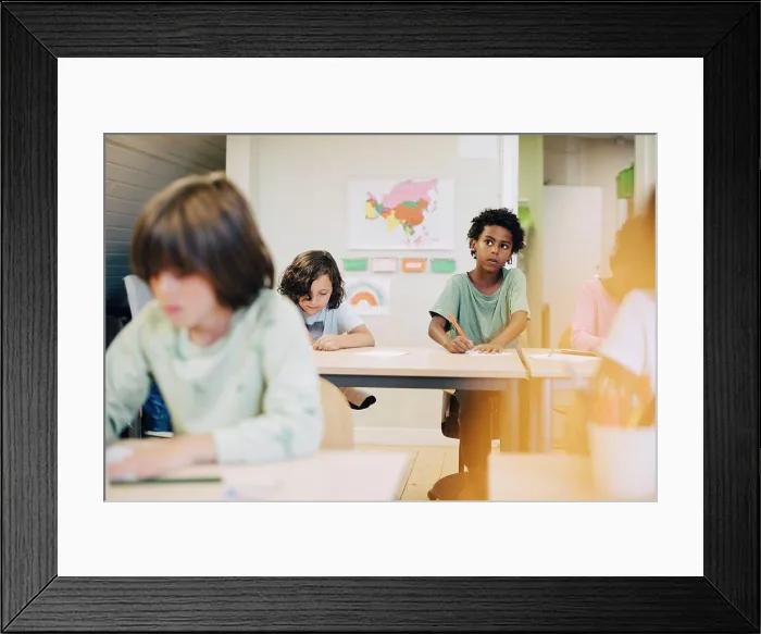 Framed Print : Curious boy drawing with friends at desk in classroom Framed Print : Curious boy drawing with friends at desk in classroom