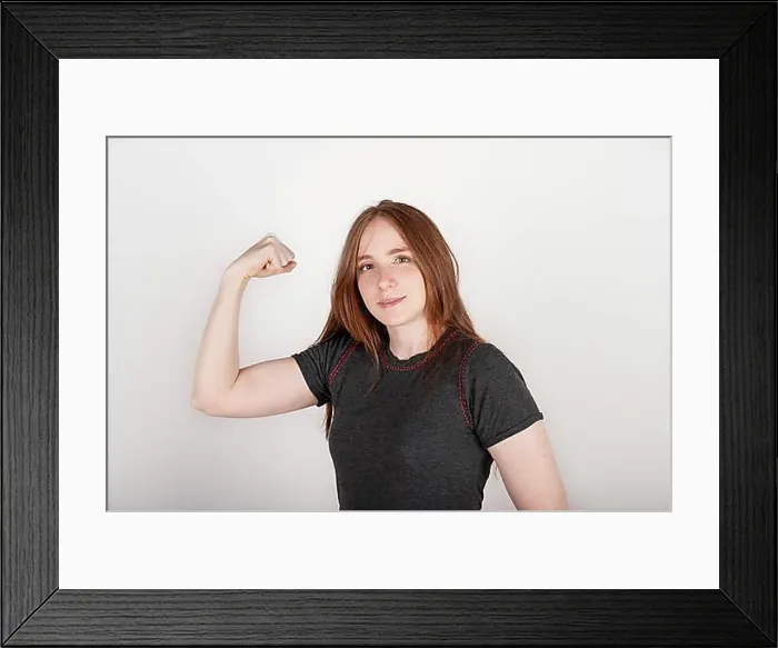Framed Print : Young red-haired woman proudly showing her bicep. Concept of feminism, girl power Framed Print : Young red-haired woman proudly showing her bicep. Concept of feminism, girl power