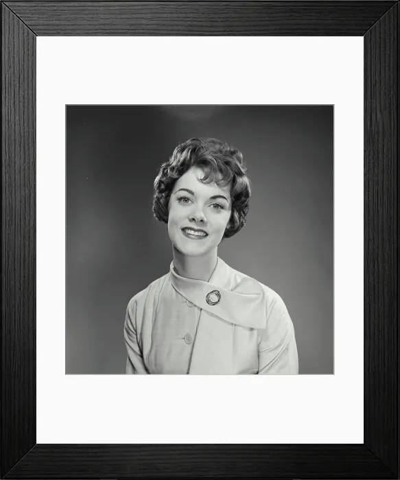 Framed Print : Vintage Photograph. Woman wears a white dress with a brooch and smiles for studio portrait while looking at the camera Framed Print : Vintage Photograph. Woman wears a white dress with a brooch and smiles for studio portrait while looking at the camera