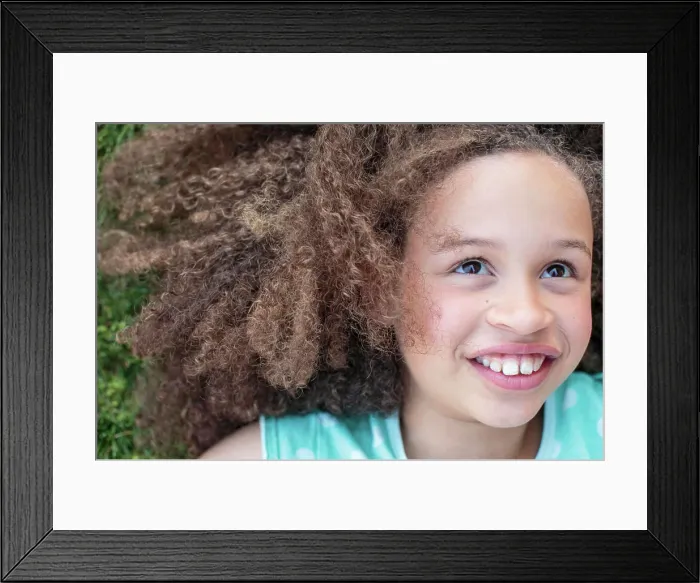 Framed Print : Young girl lying on grass, smiling offcamera with joy Framed Print : Young girl lying on grass, smiling offcamera with joy