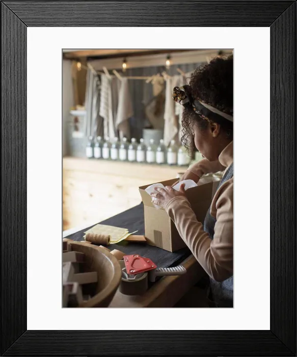 Framed Print : Female shop owner preparing package for shipping Framed Print : Female shop owner preparing package for shipping