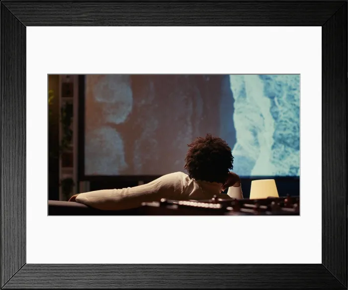 Framed Print : Man watching travel documentary with beautiful cinematography on modern video projector Framed Print : Man watching travel documentary with beautiful cinematography on modern video projector