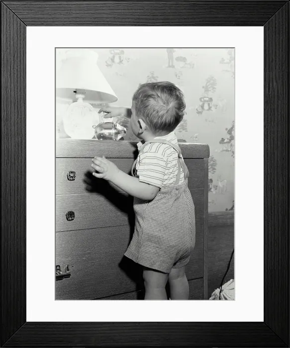 Framed Print : Vintage Photograph. Young boy placing coin in piggy bank Framed Print : Vintage Photograph. Young boy placing coin in piggy bank