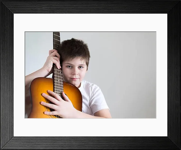 Framed Print : Teenage Boy plays an acoustic guitar while relaxing on a patio chair