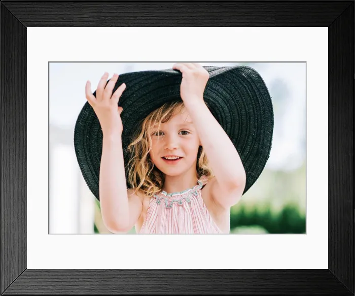 Framed Print : candid portrait of a young girl laughing playing with a large sun hat