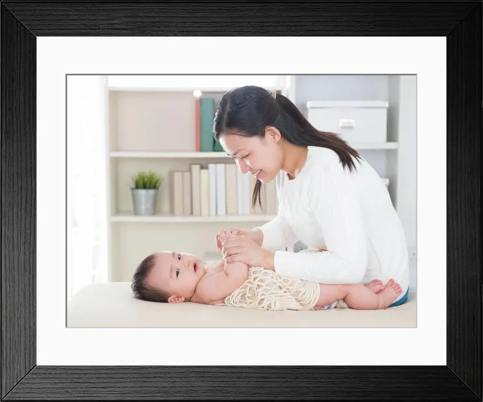 Framed Print : Baby massage. Baby massage. Asian mother massaging baby hands at home Framed Print : Baby massage. Baby massage. Asian mother massaging baby hands at home