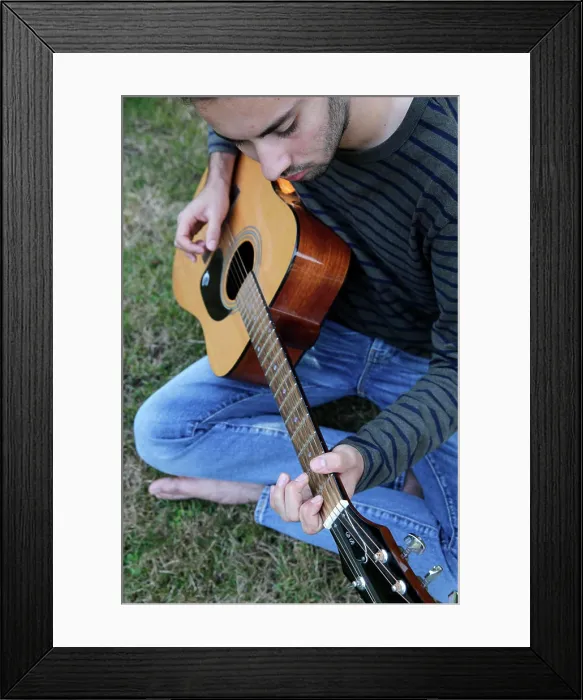 Framed Print : Young man playing a guitar in a garden. France