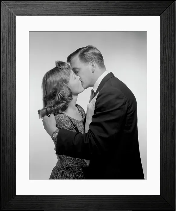 Framed Print : Young couple kissing, studio shot Framed Print : Young couple kissing, studio shot