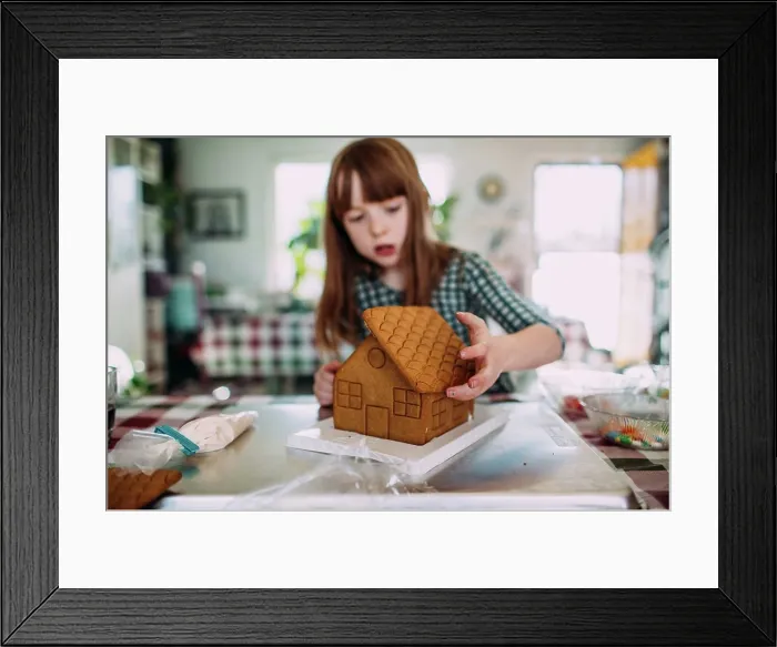 Framed Print : Young girl building a gingerbread house at the dining room table Framed Print : Young girl building a gingerbread house at the dining room table