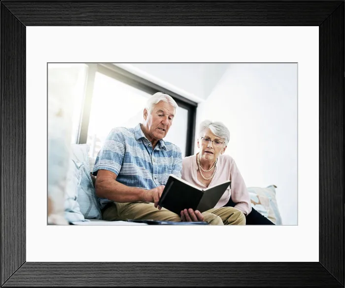 Framed Print : Senior couple, living room and reading on notebook in sofa at home with shopping list for household Framed Print : Senior couple, living room and reading on notebook in sofa at home with shopping list for household
