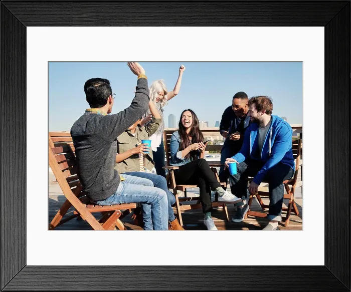 Framed Print : Group of young co-workers hanging out on rooftop patio having a drink and celebrating achievement reached on cell phone Framed Print : Group of young co-workers hanging out on rooftop patio having a drink and celebrating achievement reached on cell phone