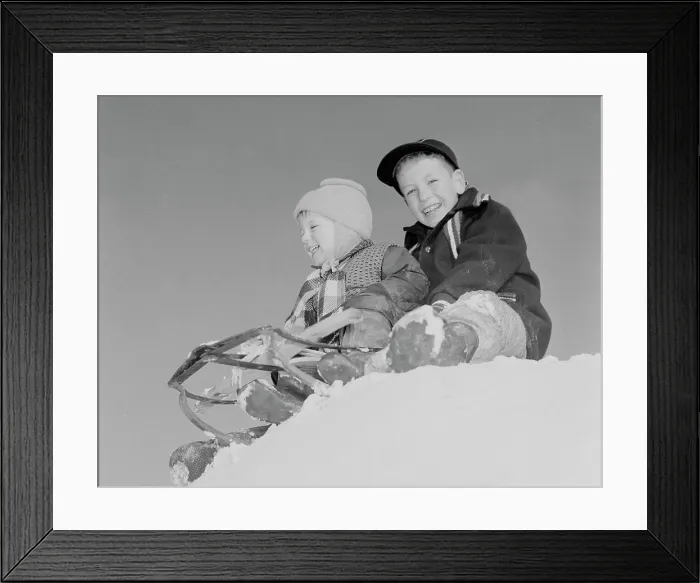 Framed Print : Pair of children sledging in winter scenery