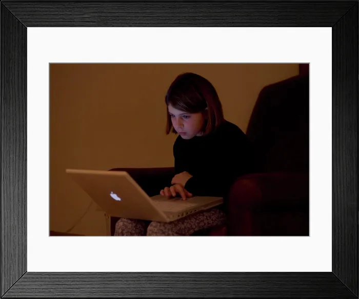Framed Print : A child works on a laptop computer, Maine, USA Framed Print : A child works on a laptop computer, Maine, USA