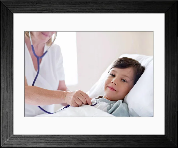 Framed Print : Boy in hospital bed, nurse using stethoscope