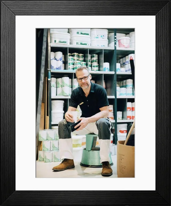 Framed Print : Full length of portrait of salesman sitting on stool in storage room Framed Print : Full length of portrait of salesman sitting on stool in storage room