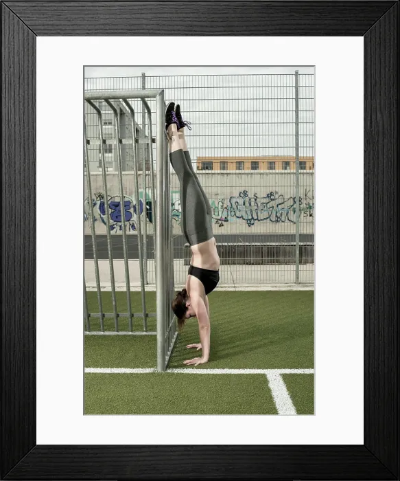 Framed Print : Young woman doing handstand on football ground, Bavaria, Germany