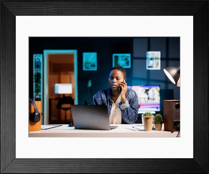 Framed Print : Multitasking professional efficiently manages a conversation on her mobile device while simultaneously working