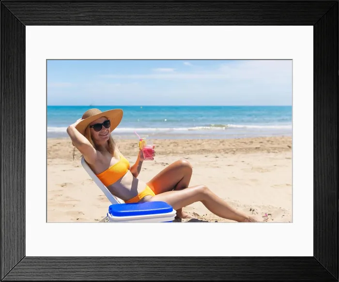 Framed Print : Happy young european girl drinks a cocktail and rests in a sun lounger on the beach Framed Print : Happy young european girl drinks a cocktail and rests in a sun lounger on the beach