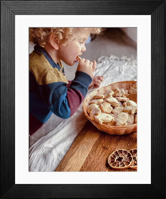 Framed Print : the child tastes fresh cookies with tea Framed Print : the child tastes fresh cookies with tea