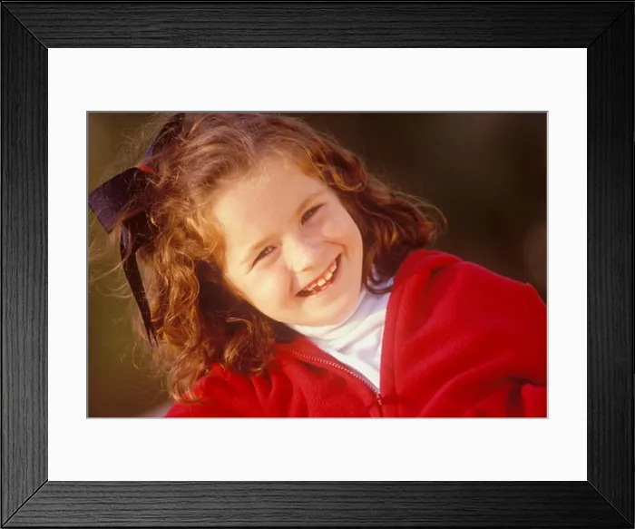 Framed Print : Medium close up of a cute young girl with freckles looking at the camera and smiling Framed Print : Medium close up of a cute young girl with freckles looking at the camera and smiling