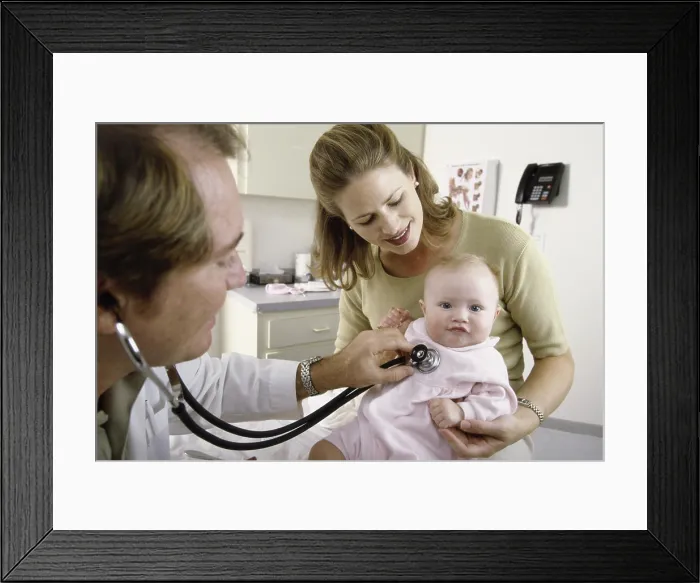 Framed Print : Male doctor examining a baby girl