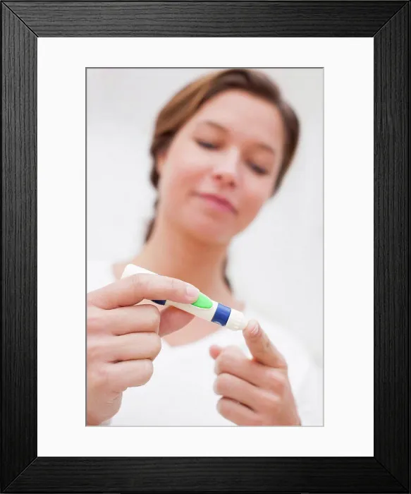 Framed Print : Woman doing finger prick test for blood glucose Framed Print : Woman doing finger prick test for blood glucose