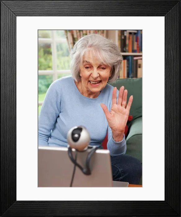 Framed Print : Senior Woman Using Webcam To Talk With Family Framed Print : Senior Woman Using Webcam To Talk With Family
