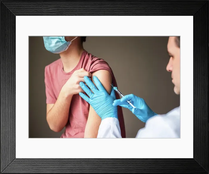 Framed Print : Teen boy wearing mask getting vaccinated by doctor holding a needle Framed Print : Teen boy wearing mask getting vaccinated by doctor holding a needle