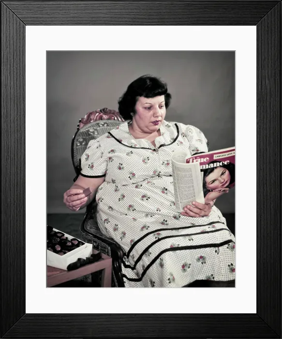 Framed Print : 1950s OBESE OVERWEIGHT WOMAN SITTING EATING BOX OF CHOCOLATE CANDY READING MOVIE FAN MAGAZINE