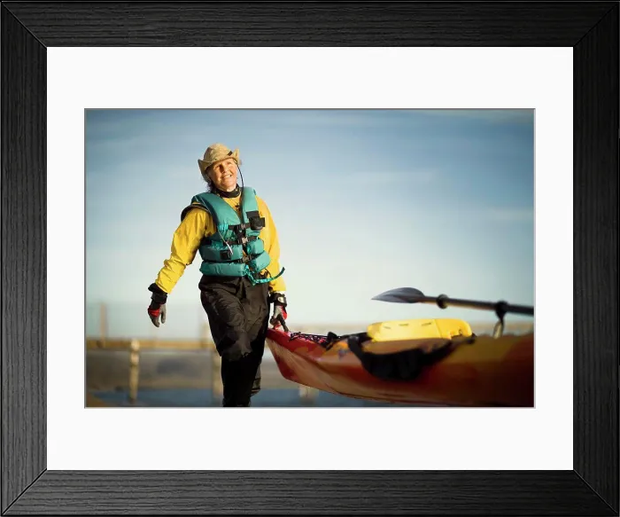 Framed Print : Smiling senior woman carrying the end of a kayak in the sunshine