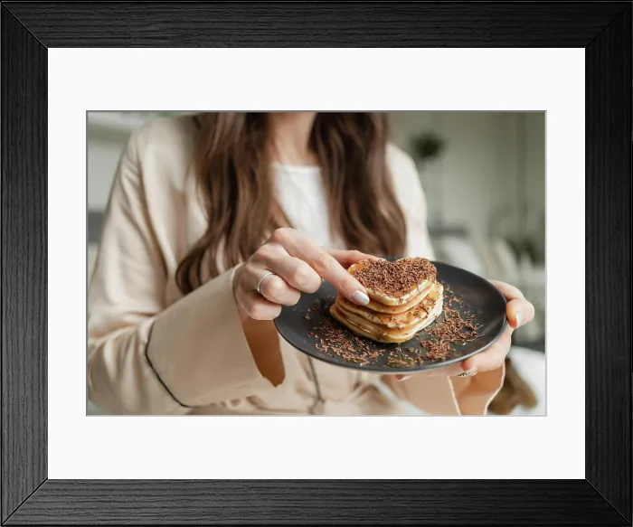 Framed Print : Woman trying heart shaped pancakes with grated chocolate for breakfast Framed Print : Woman trying heart shaped pancakes with grated chocolate for breakfast