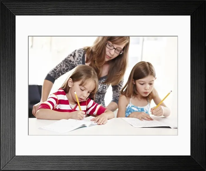 Framed Print : Mother helping two daughters with homework
