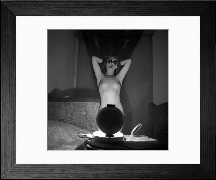 Framed Print : Beauty care in the 1950s. A young woman is getting a tan by the artificial sunlight from the home tanning sunlamp