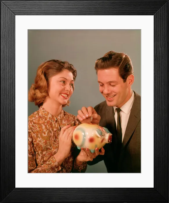 Framed Print : 1950S 1960S Happy Smiling Couple Man Woman Putting Coins Into Savings Piggy Bank