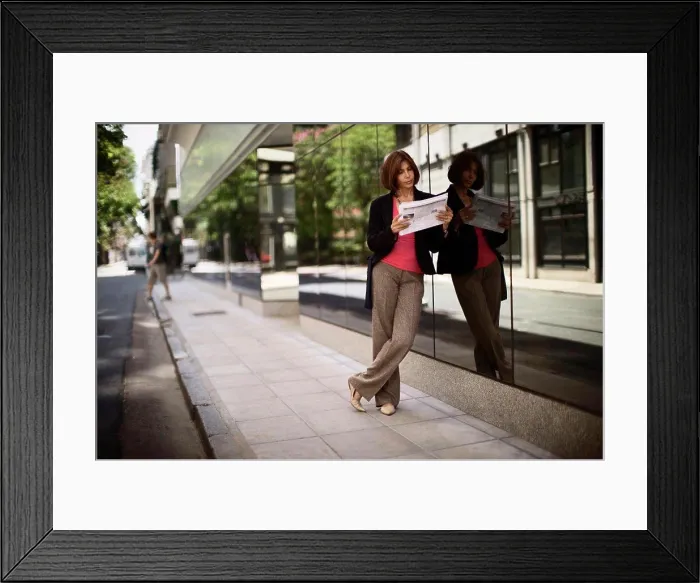 Framed Print : Side view of a stylish woman reading a newspaper Framed Print : Side view of a stylish woman reading a newspaper
