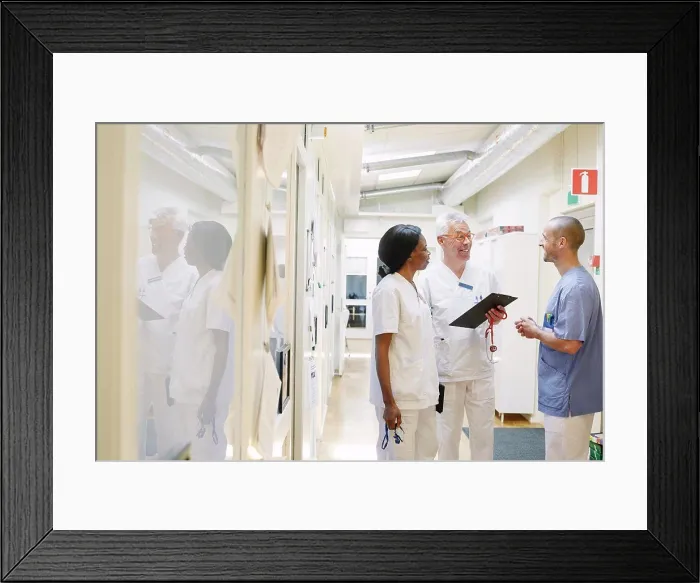 Framed Print : Smiling multi-ethnic doctors discussing while standing in hospital corridor Framed Print : Smiling multi-ethnic doctors discussing while standing in hospital corridor