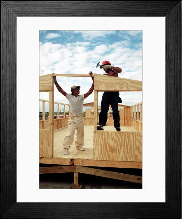 Framed Print : A Cuban migrant carpenter hammers in the nails as another migrant holds the frame during the construction of hard back Framed Print : A Cuban migrant carpenter hammers in the nails as another migrant holds the frame during the construction of hard back