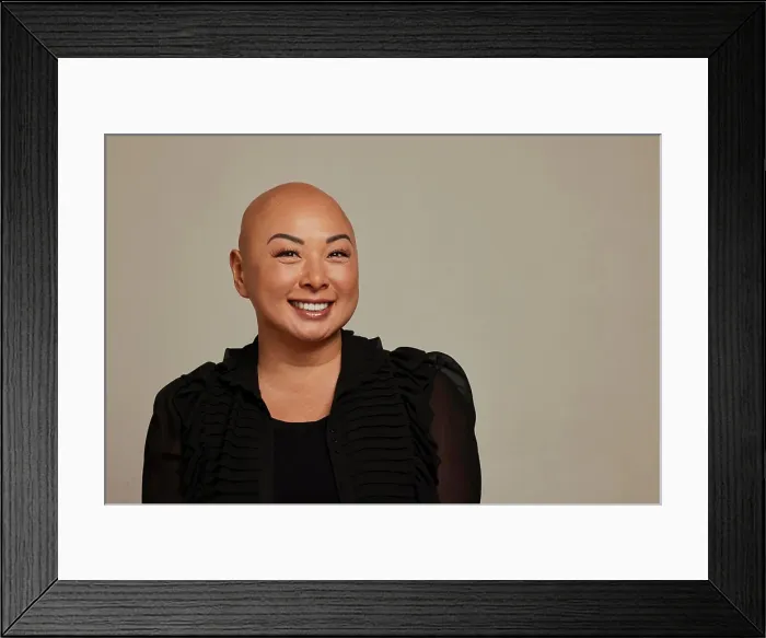 Framed Print : Confident bald woman in stylish outfit smiling against a neutral background