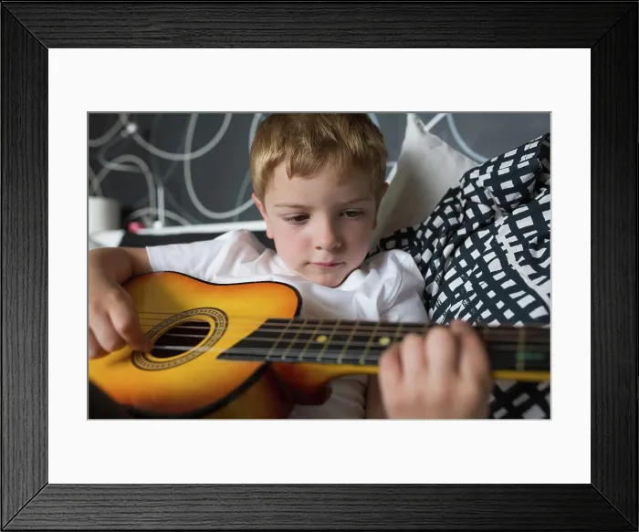Framed Print : Young blonde boy playing toy guitar Framed Print : Young blonde boy playing toy guitar
