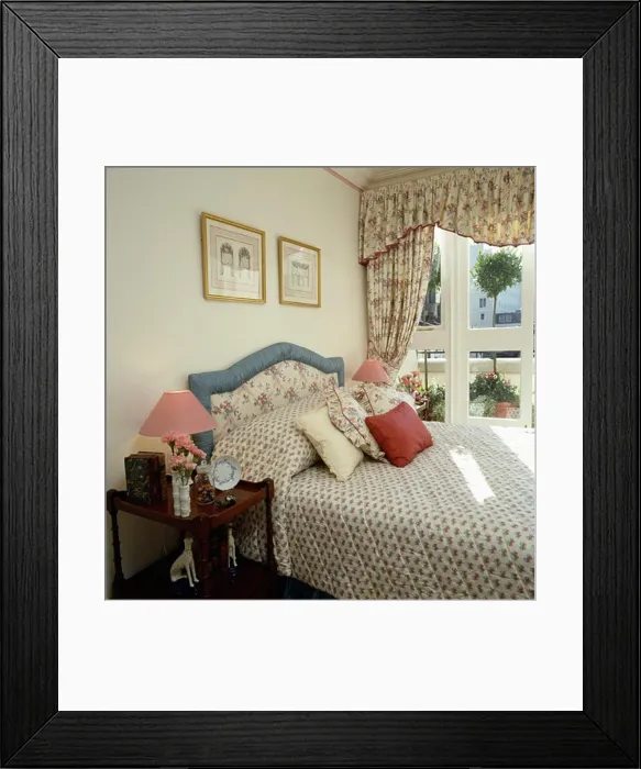 Framed Print : Floral curtains and toning quilt and upholstered headboard in traditional bedroom