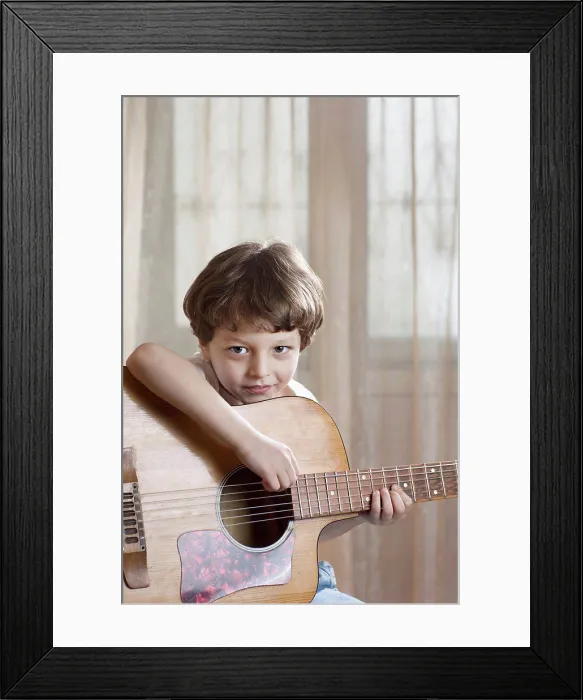 Framed Print : A young boy holding an acoustic guitar