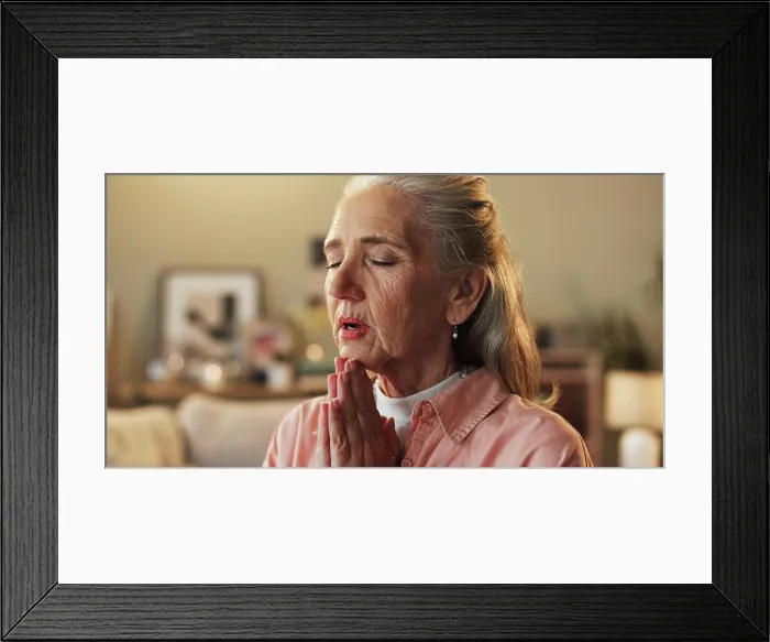Framed Print : Belief, hope and prayer with senior woman on sofa in living room of home for trust in Christ Jesus