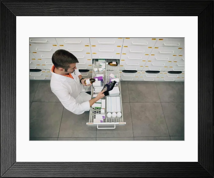 Framed Print : High angle view of pharmacist holding digital tablet checking medicine bottle at store Framed Print : High angle view of pharmacist holding digital tablet checking medicine bottle at store