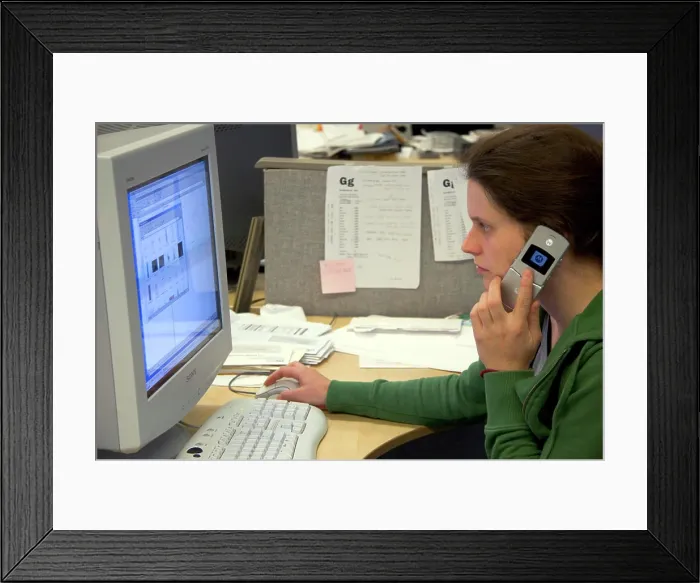 Framed Print : Office worker using a computer and cell phone. MR Framed Print : Office worker using a computer and cell phone. MR