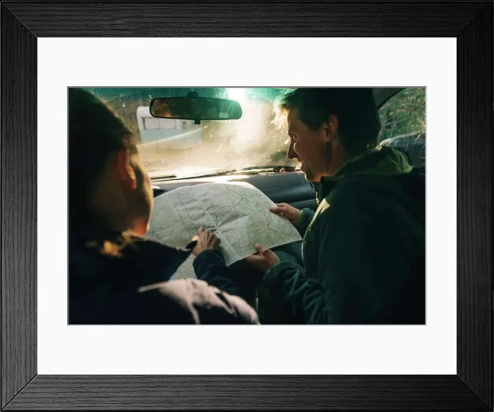 Framed Print : A young couple looks at the map on a road trip