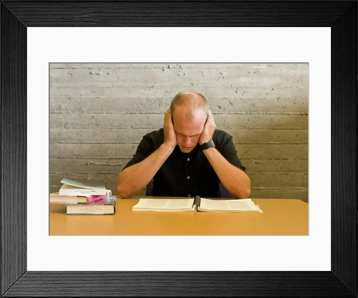 Framed Print : Young man reading and studying in a library Framed Print : Young man reading and studying in a library