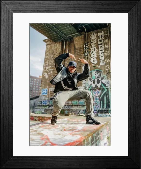 Framed Print : Street dancer strikes pose on graffiti-covered ledge under bridge