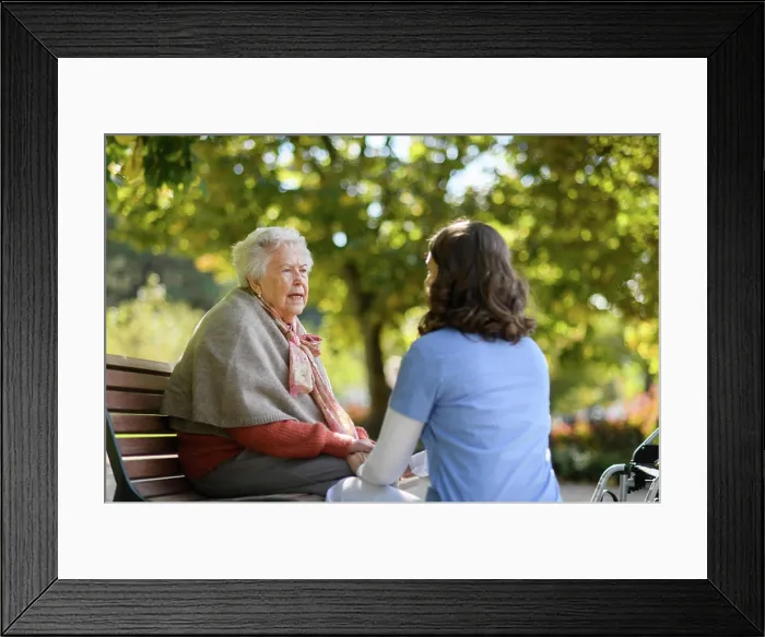 Framed Print : Portrait of nurse and elderly woman sitting on bench in park during warm autumn day Framed Print : Portrait of nurse and elderly woman sitting on bench in park during warm autumn day