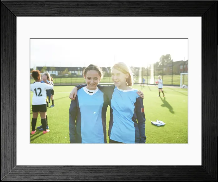 Framed Print : UK, Portrait of female soccer team members embracing in field